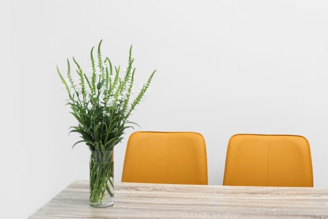 Beautiful bouquet in vase on wooden table against color background. Stylish interior